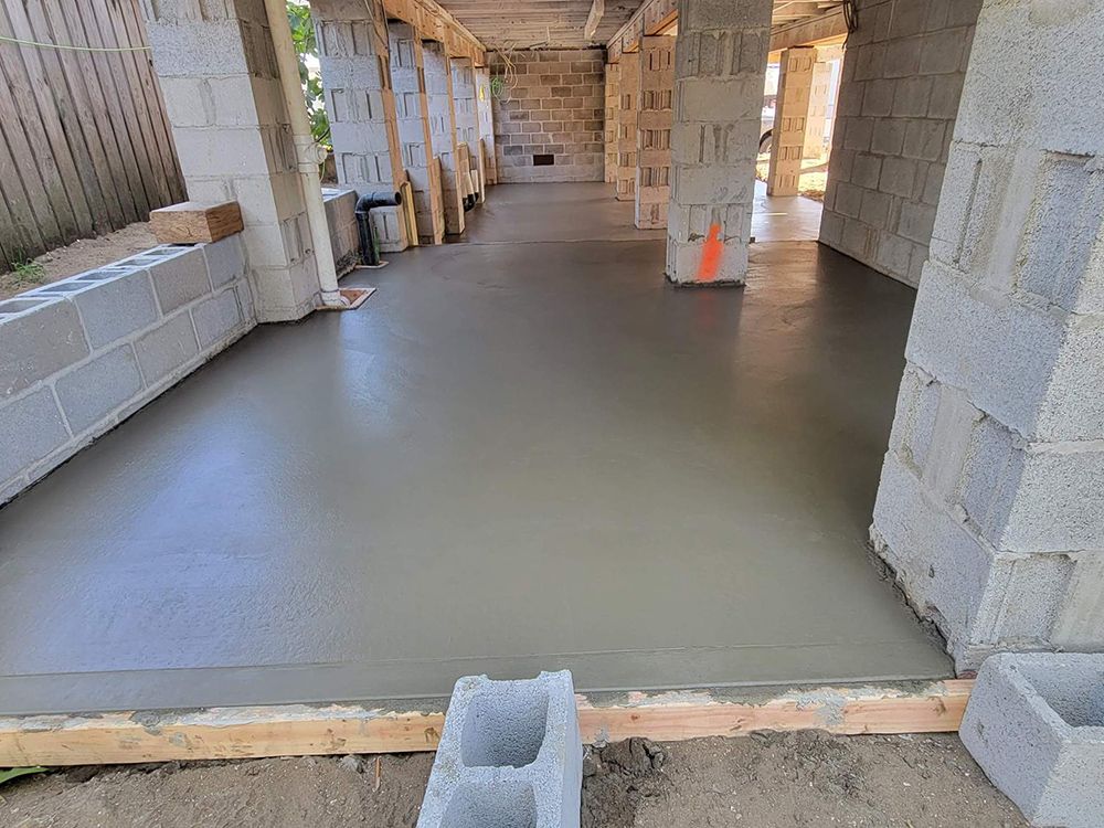 A concrete floor is being poured in a building under construction.