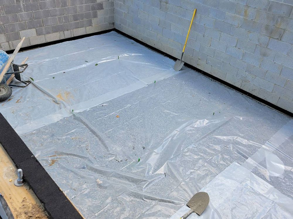 A shovel is sitting on a piece of plastic on the floor.