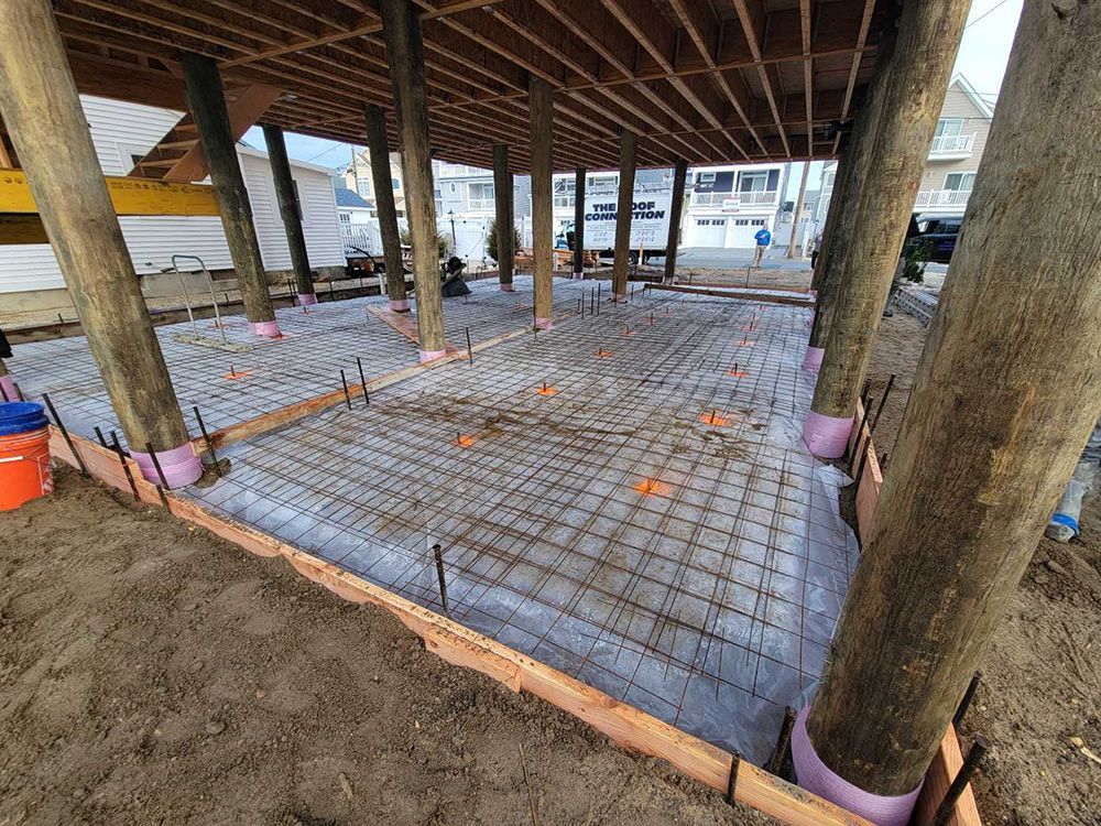 A concrete floor is being poured under a wooden structure.