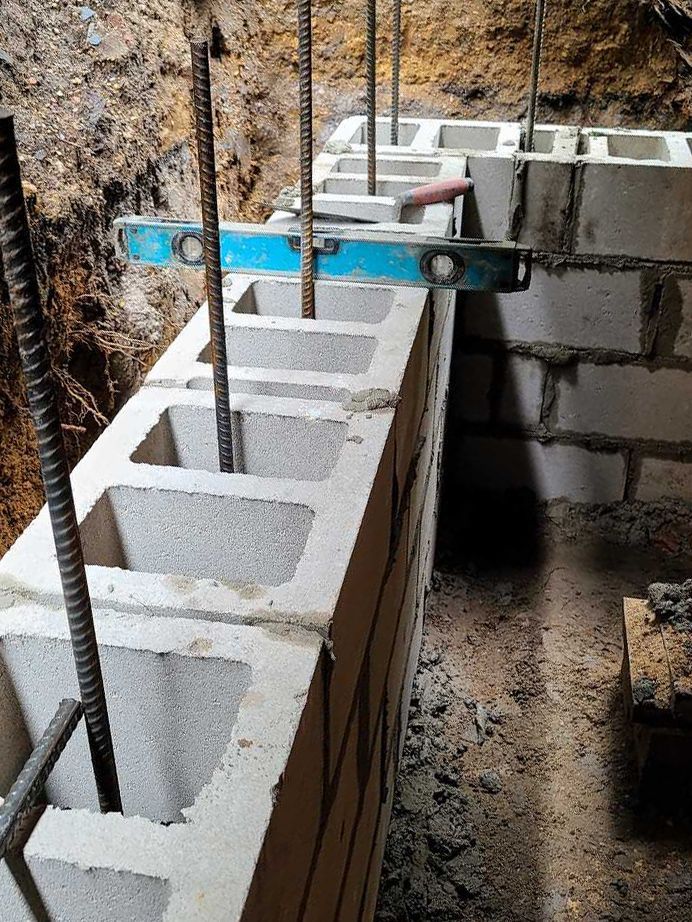 A brick wall is being built with a blue level on top of it.