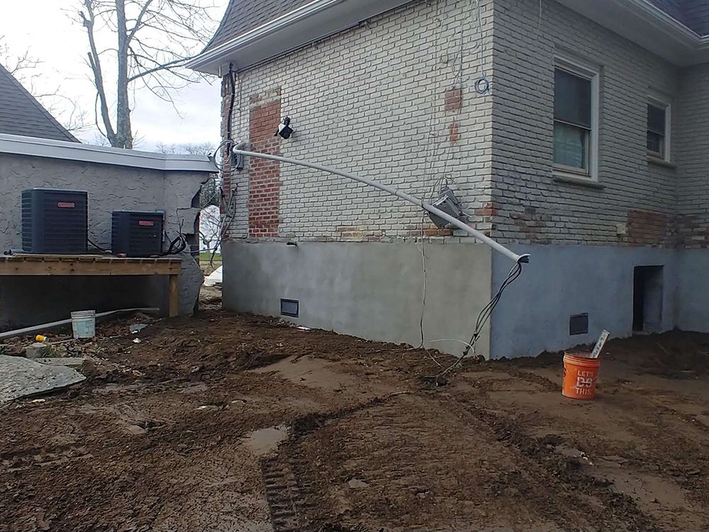 A white brick house with a bucket of dirt in front of it.