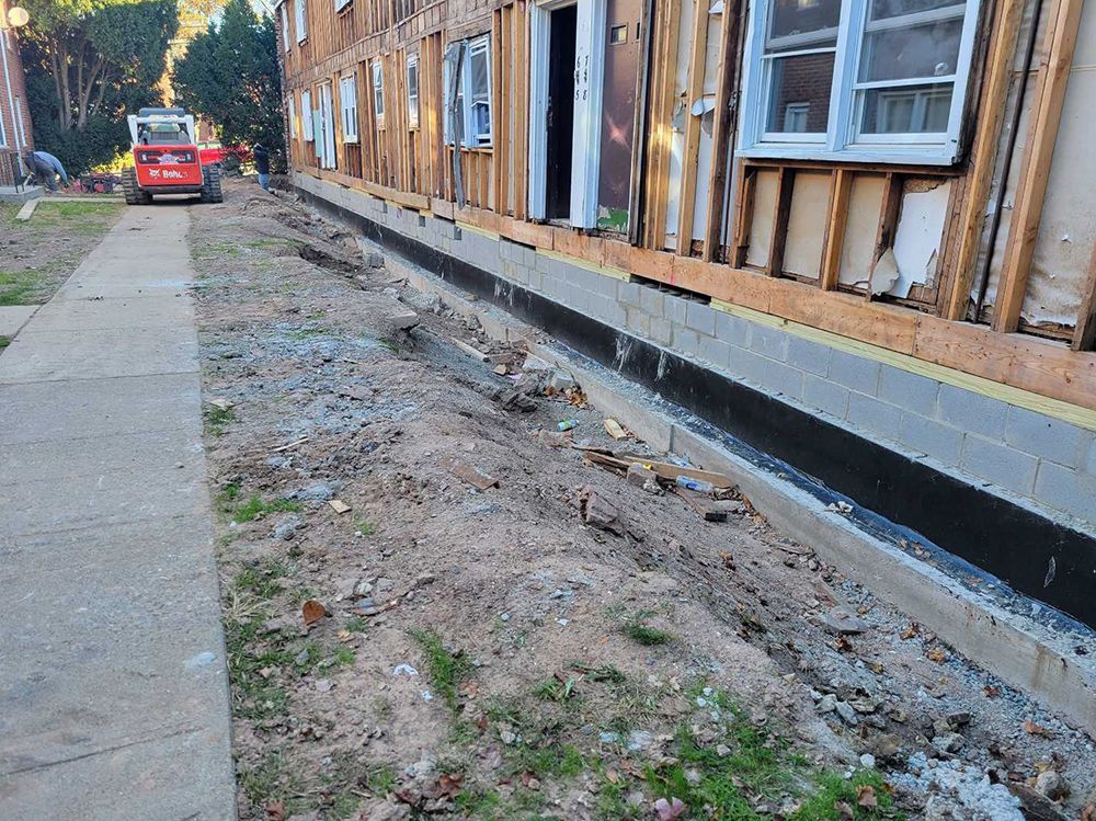 A red car is parked in front of a building under construction.
