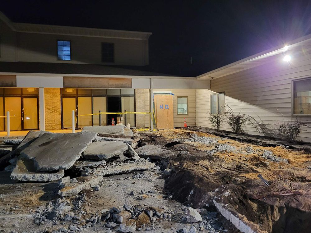 A building under construction at night with a lot of dirt in front of it.