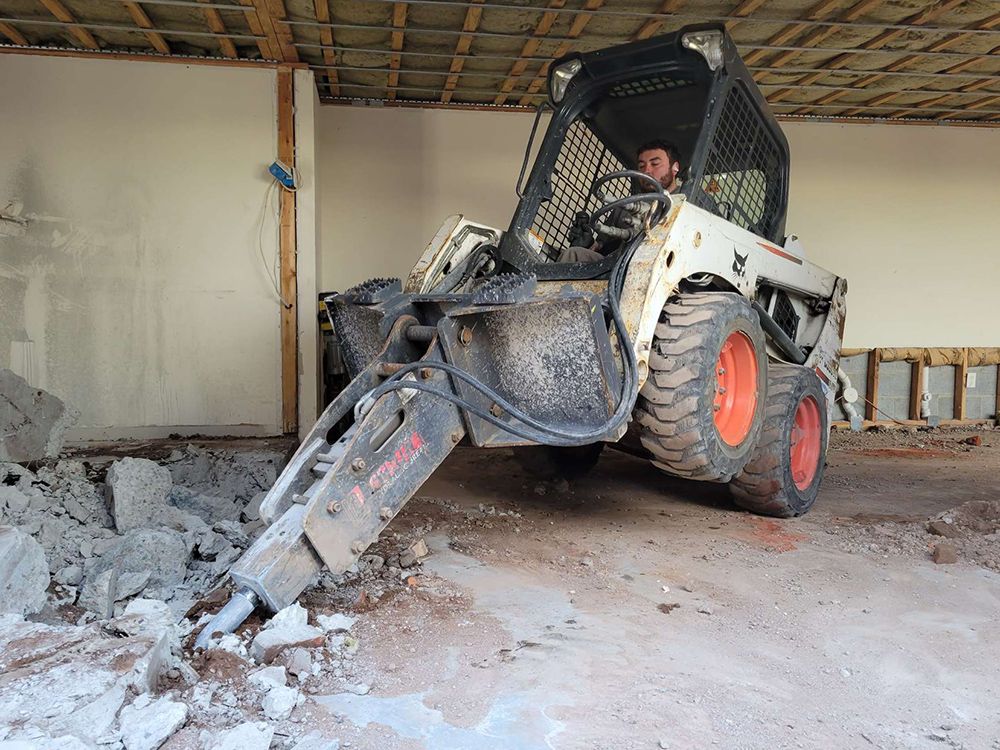 A man is driving a bobcat in a building.