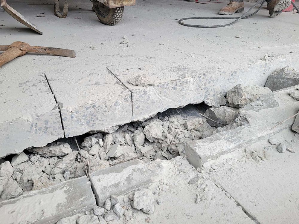 A person is cutting a hole in a concrete floor.