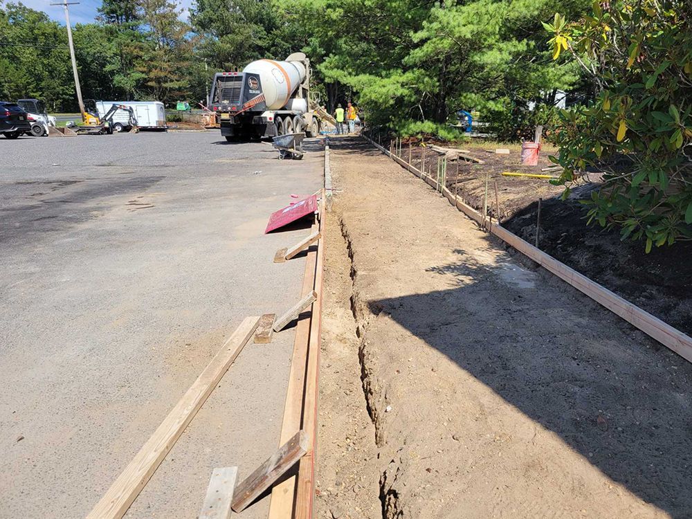 A concrete mixer is pouring concrete on a sidewalk.