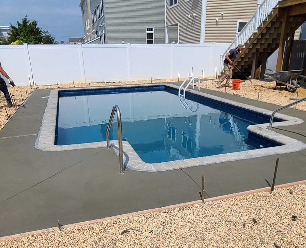 A large swimming pool is being built in the backyard of a house.