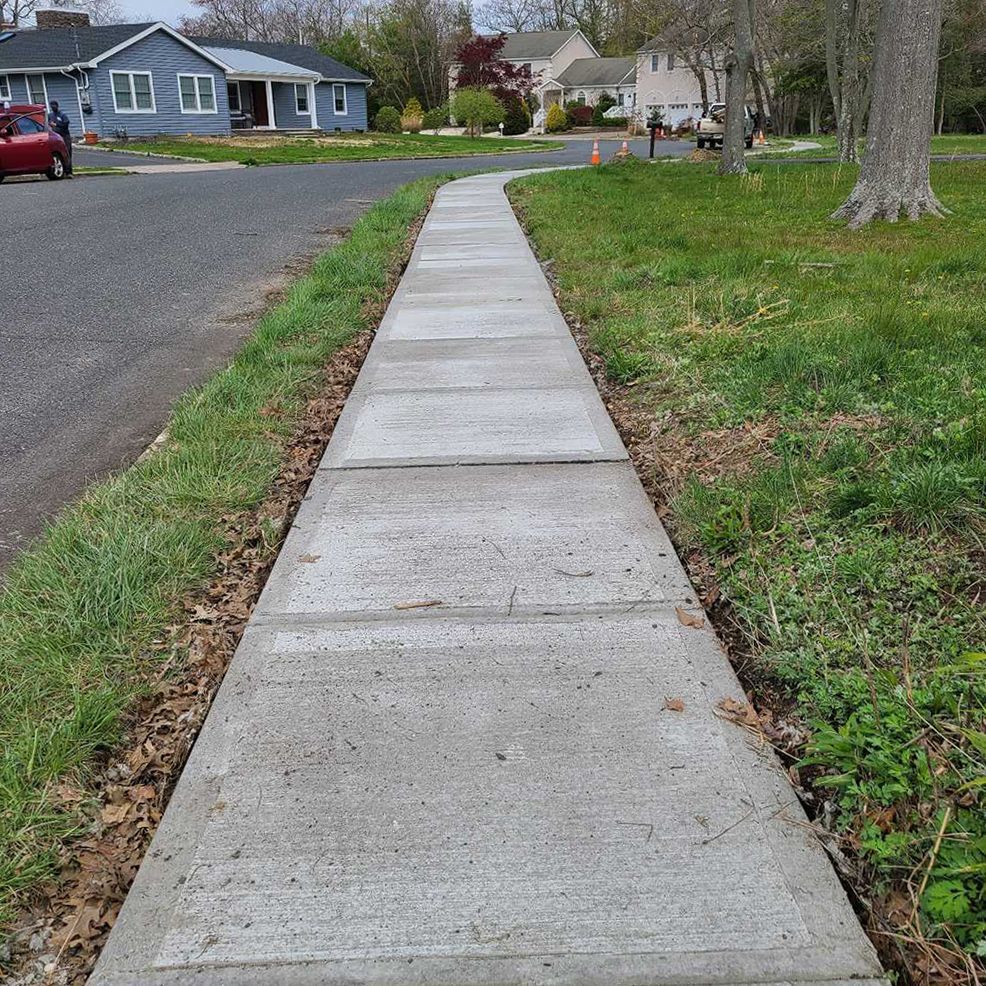 A concrete walkway leading to a house in a residential neighborhood