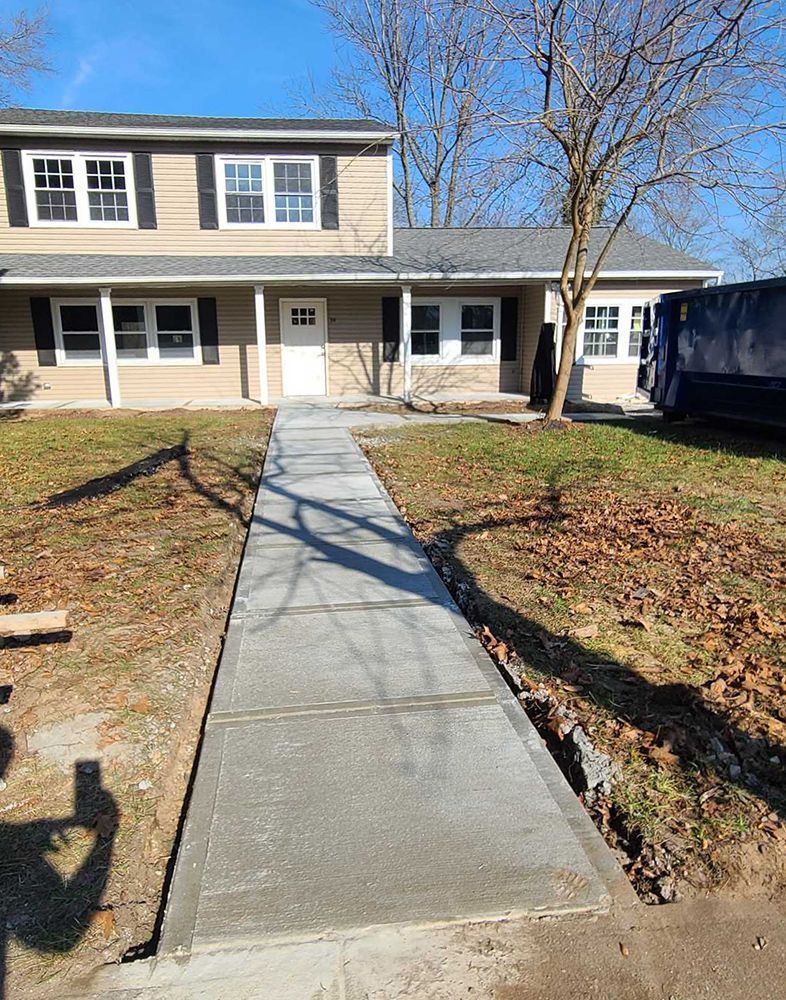 A concrete walkway leading to a house on a sunny day.