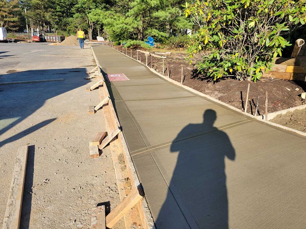 A shadow of a person is cast on a concrete sidewalk.