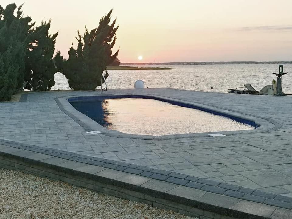 A swimming pool with a view of the ocean at sunset