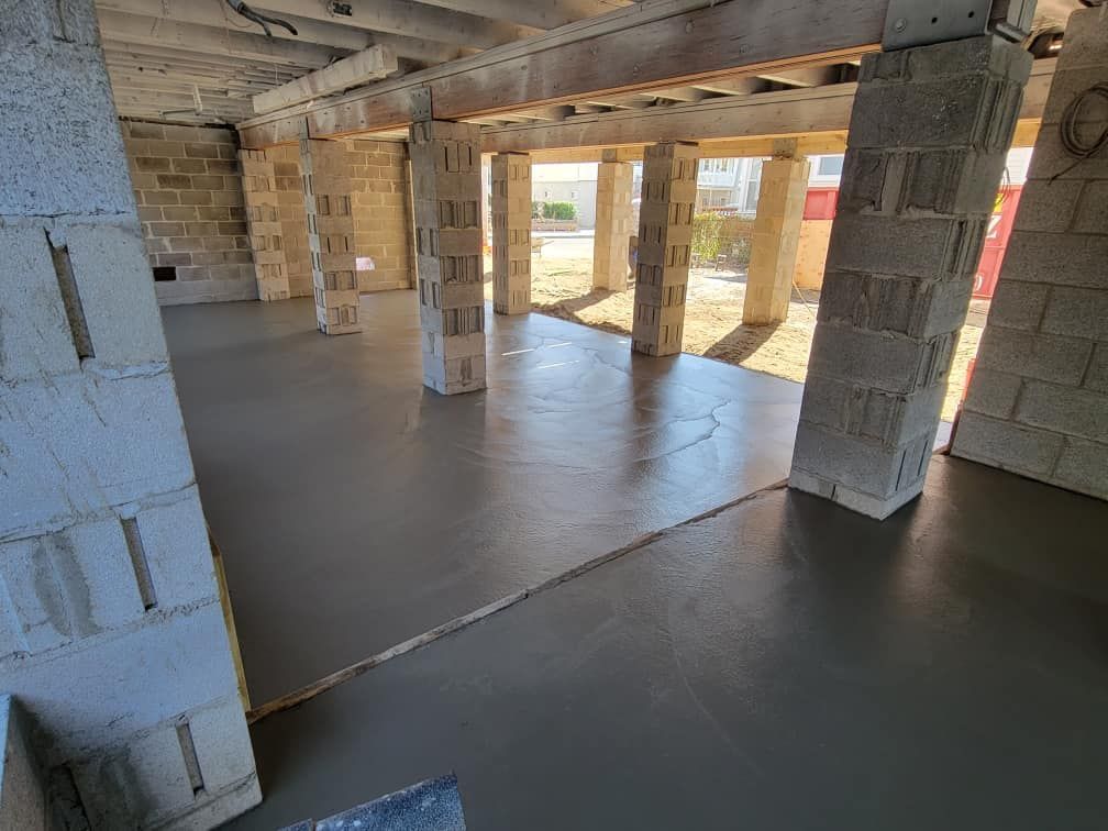 A concrete floor is being poured in a building under construction.