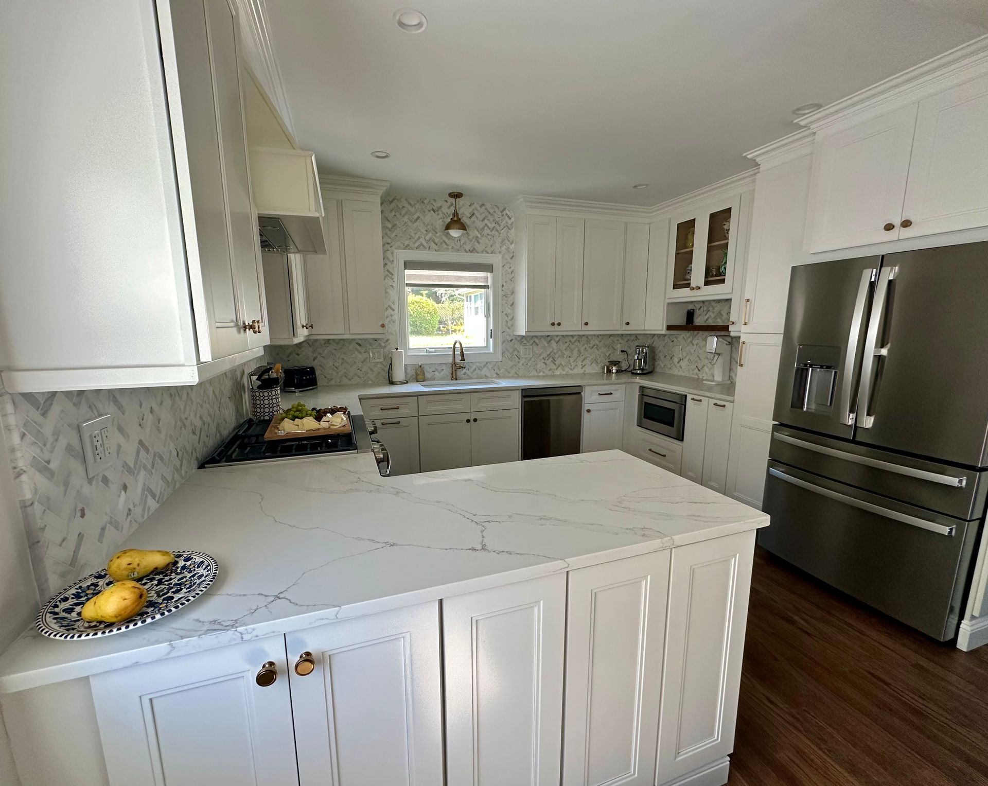 White kitchen with marble countertops, stainless steel appliances, and white cabinets.
