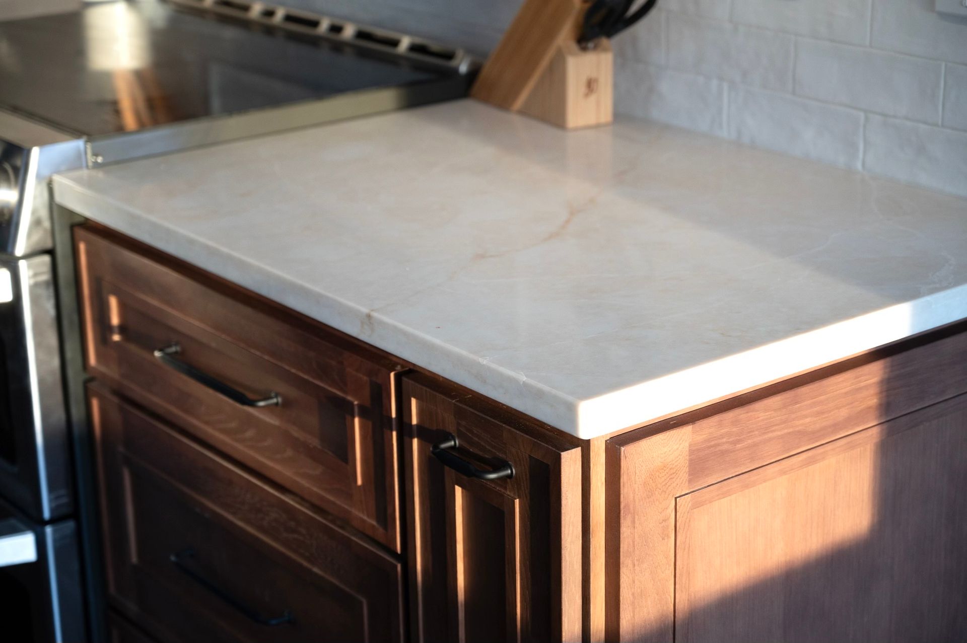 Kitchen countertop, light stone color, over dark wood cabinets. 