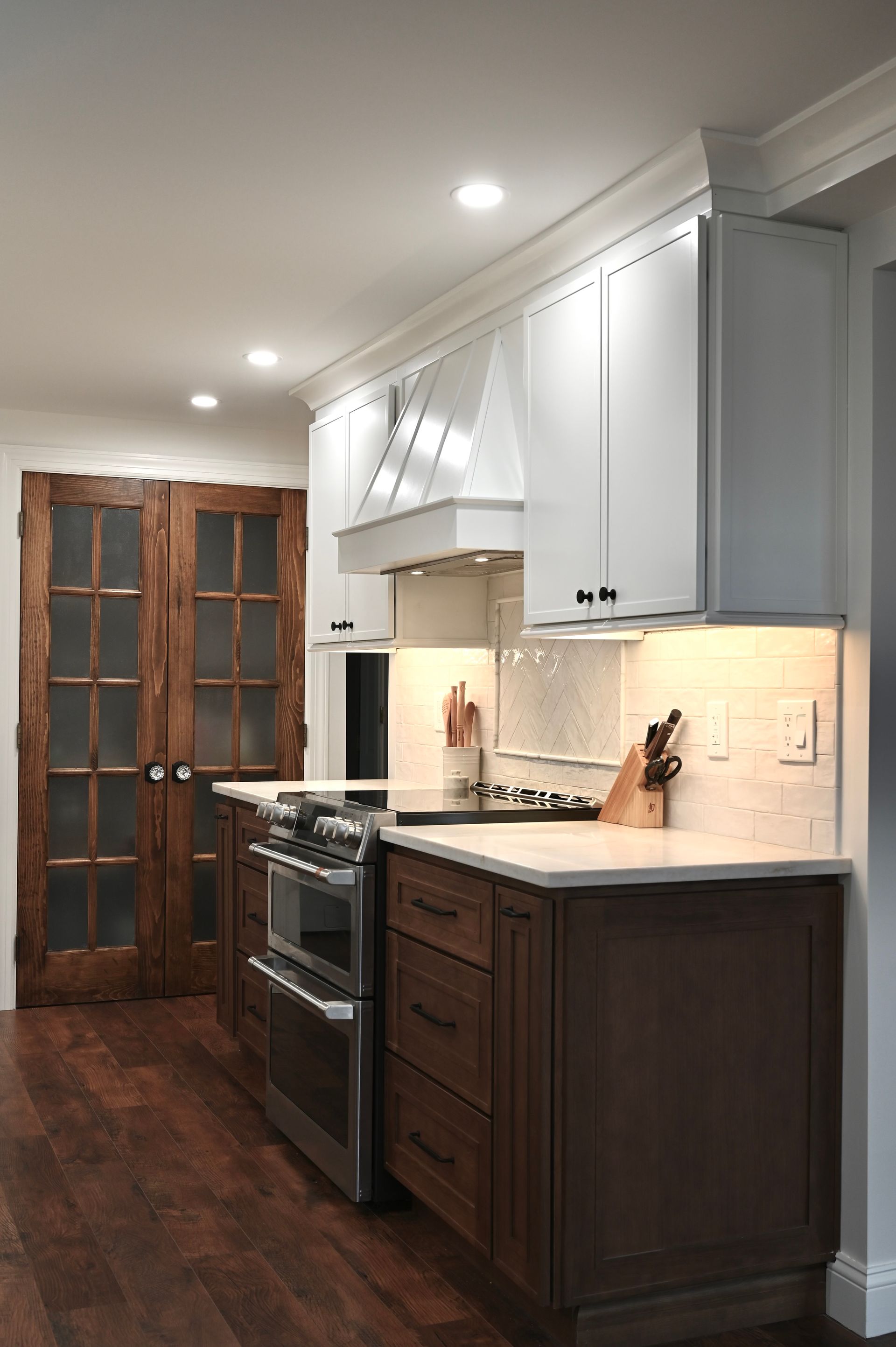 Kitchen with white and brown cabinets, stainless steel stove, and wooden floor.