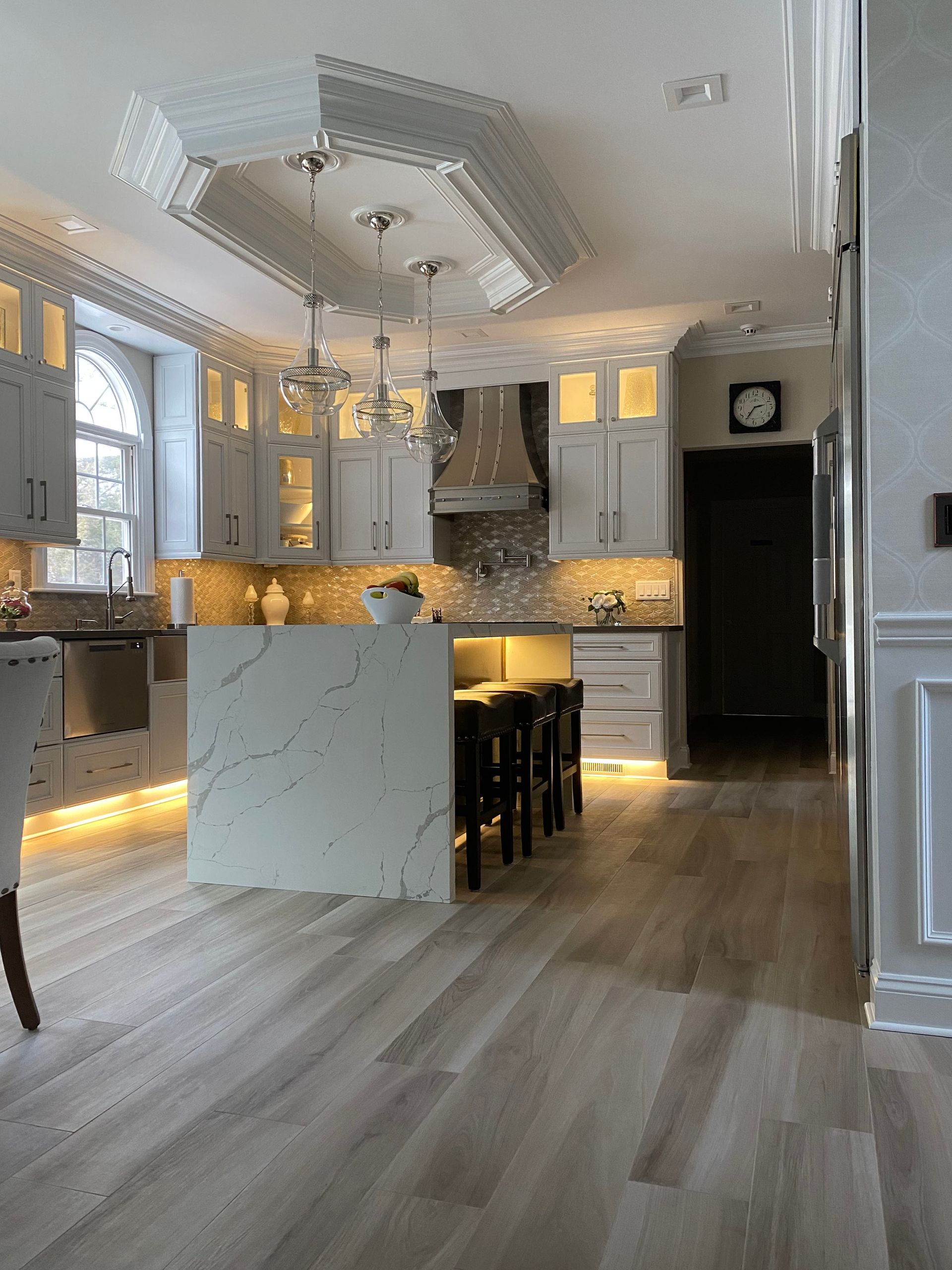 Elegant kitchen with light gray cabinetry, marble island, and hardwood floors.