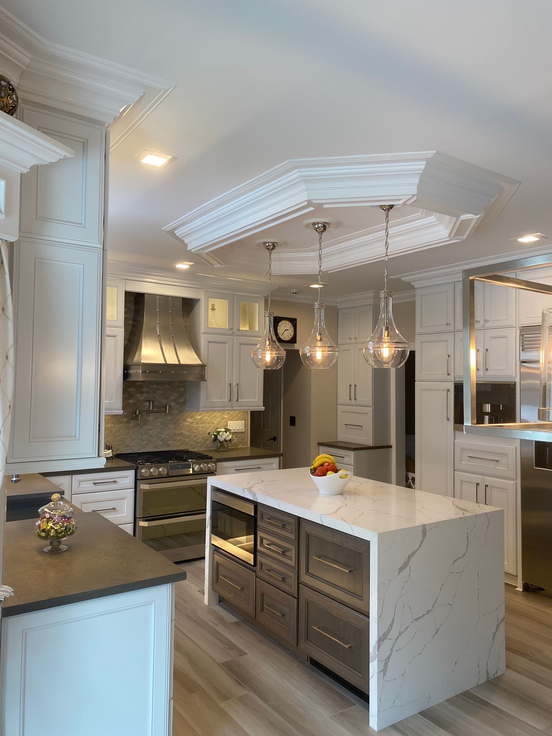 Modern white kitchen with island, stainless steel appliances, and pendant lights.