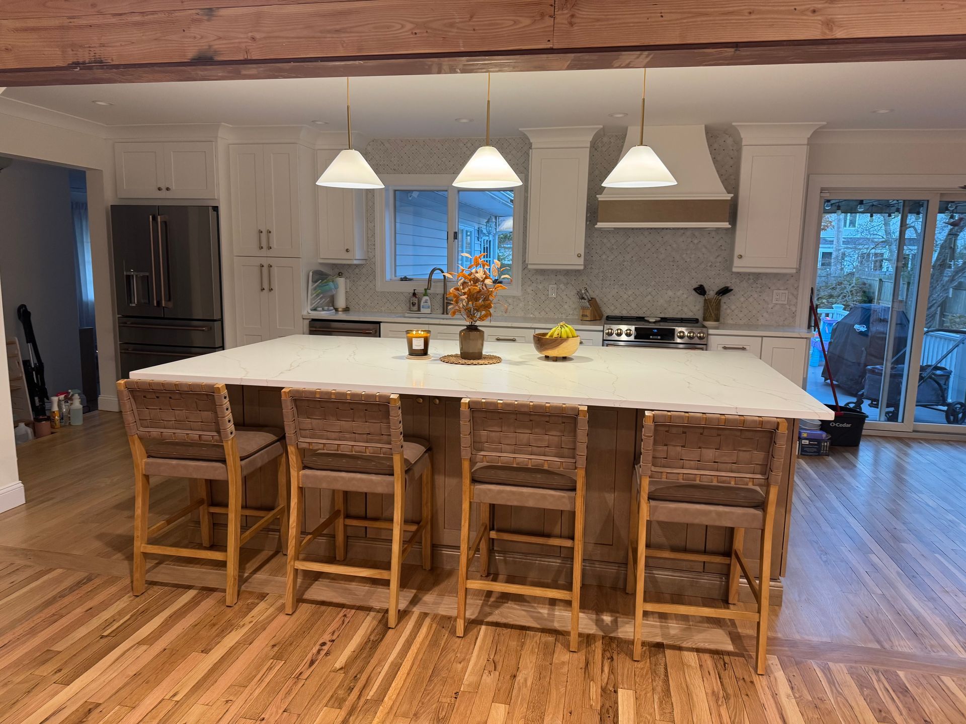 Kitchen with white cabinets, a large island with seating, pendant lights, and a sliding glass door.