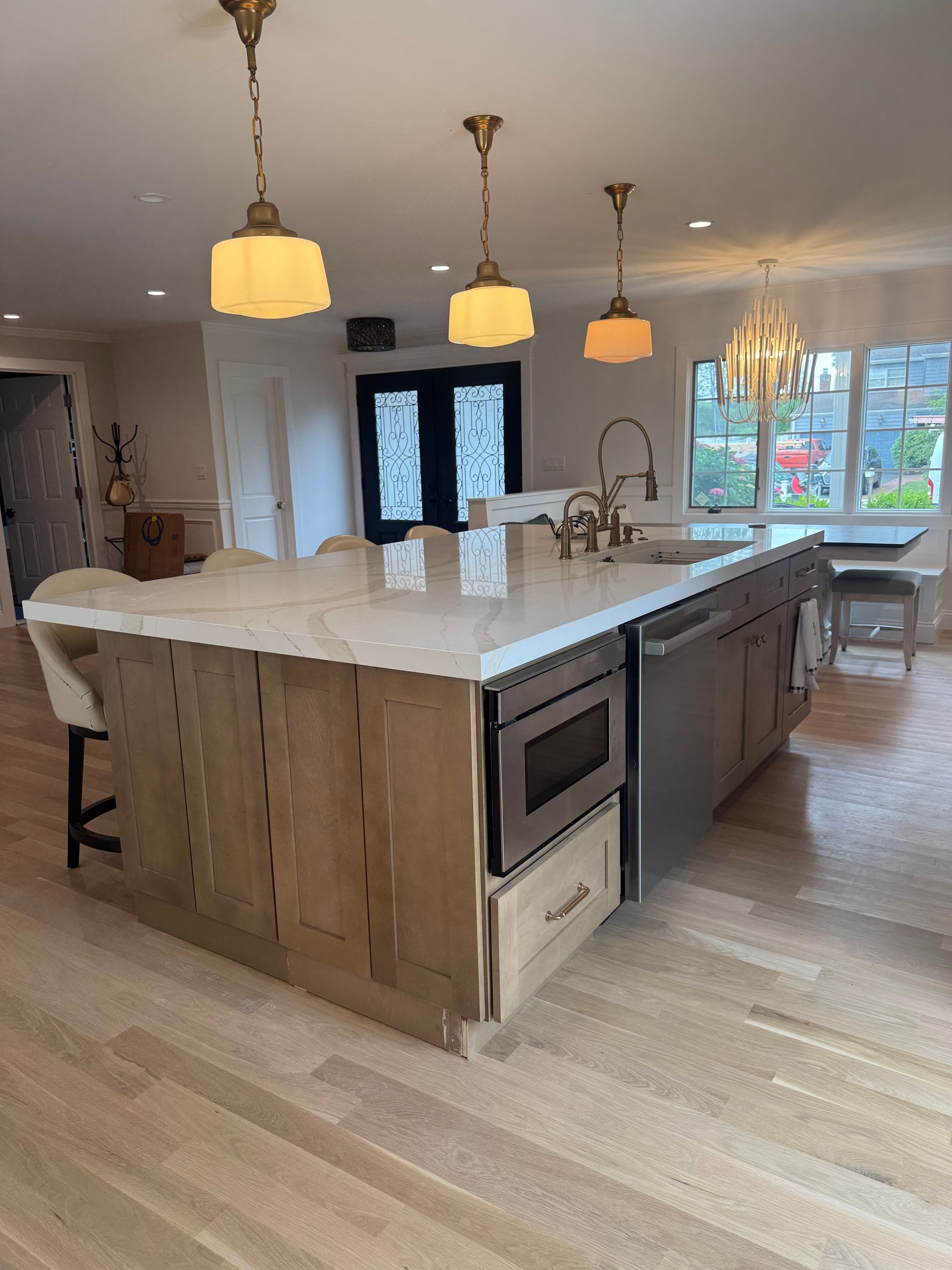 Kitchen island with a light-colored countertop, built-in microwave, and wood paneling. 