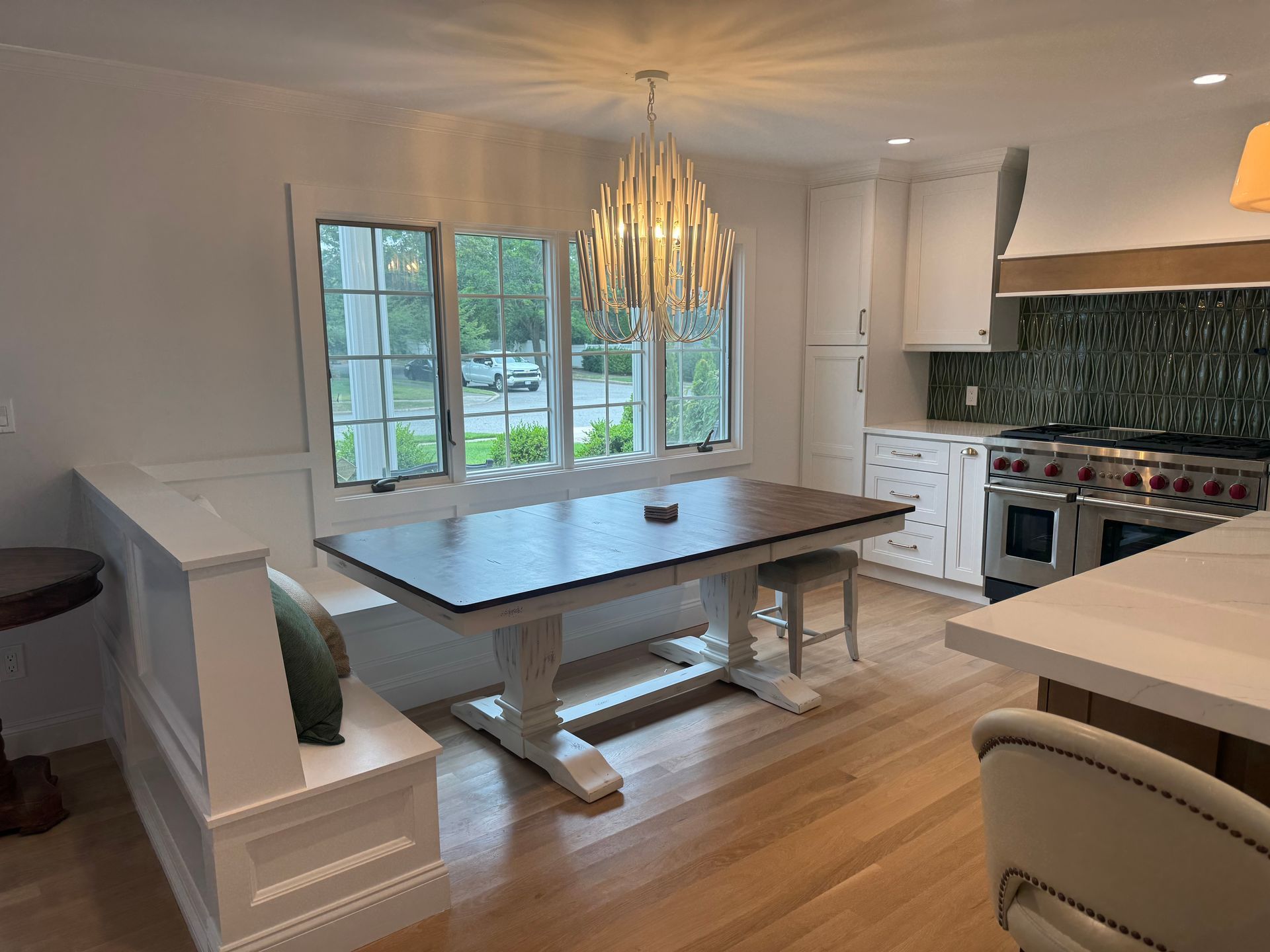Kitchen with dining table, built-in bench, windows, and chandelier.