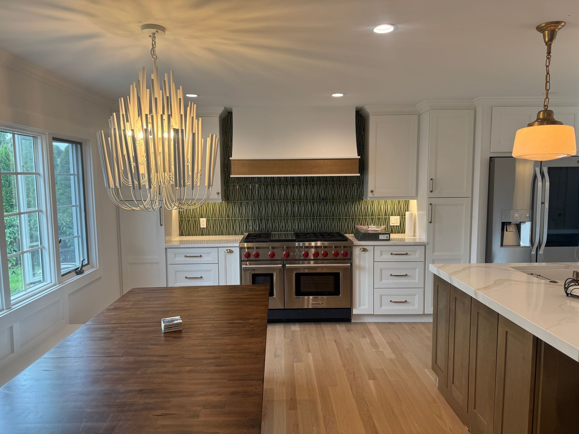 Elegant kitchen with white cabinets, wood island, and a decorative light fixture over the stove.