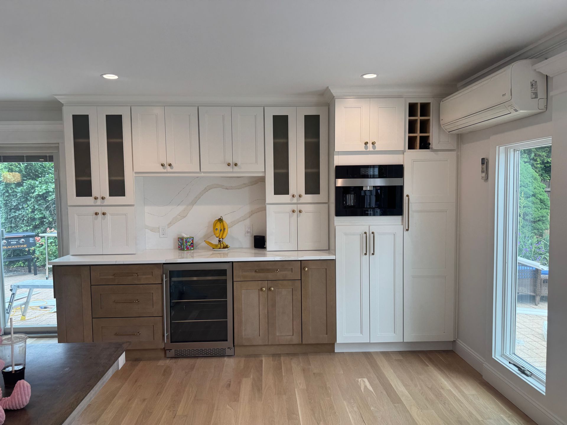 Modern kitchen with white and brown cabinets, built-in appliances, and a wine cooler.