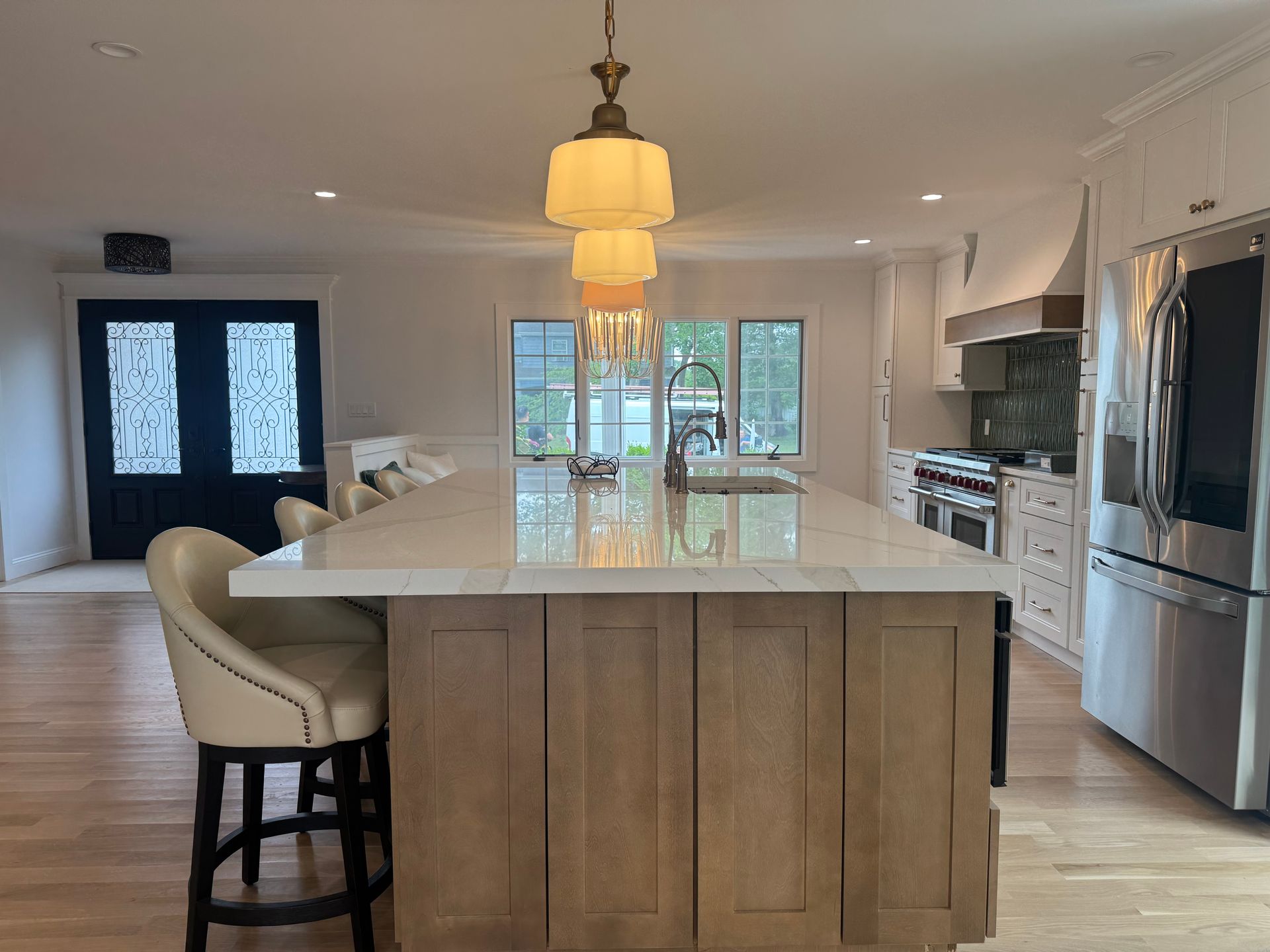 Spacious kitchen with large island, pendant lights, stainless steel appliances, and wood cabinets.