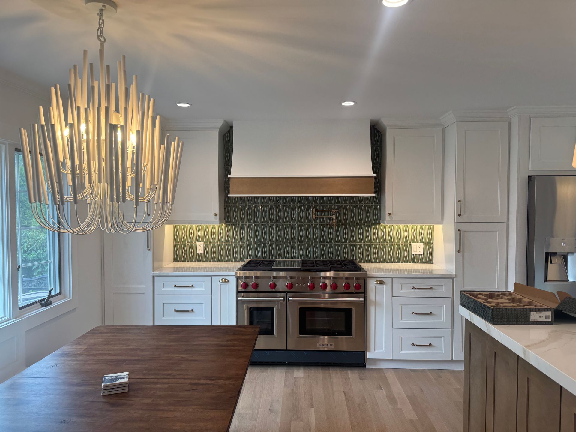 Kitchen with white cabinets, stainless steel range, patterned backsplash, and chandelier.