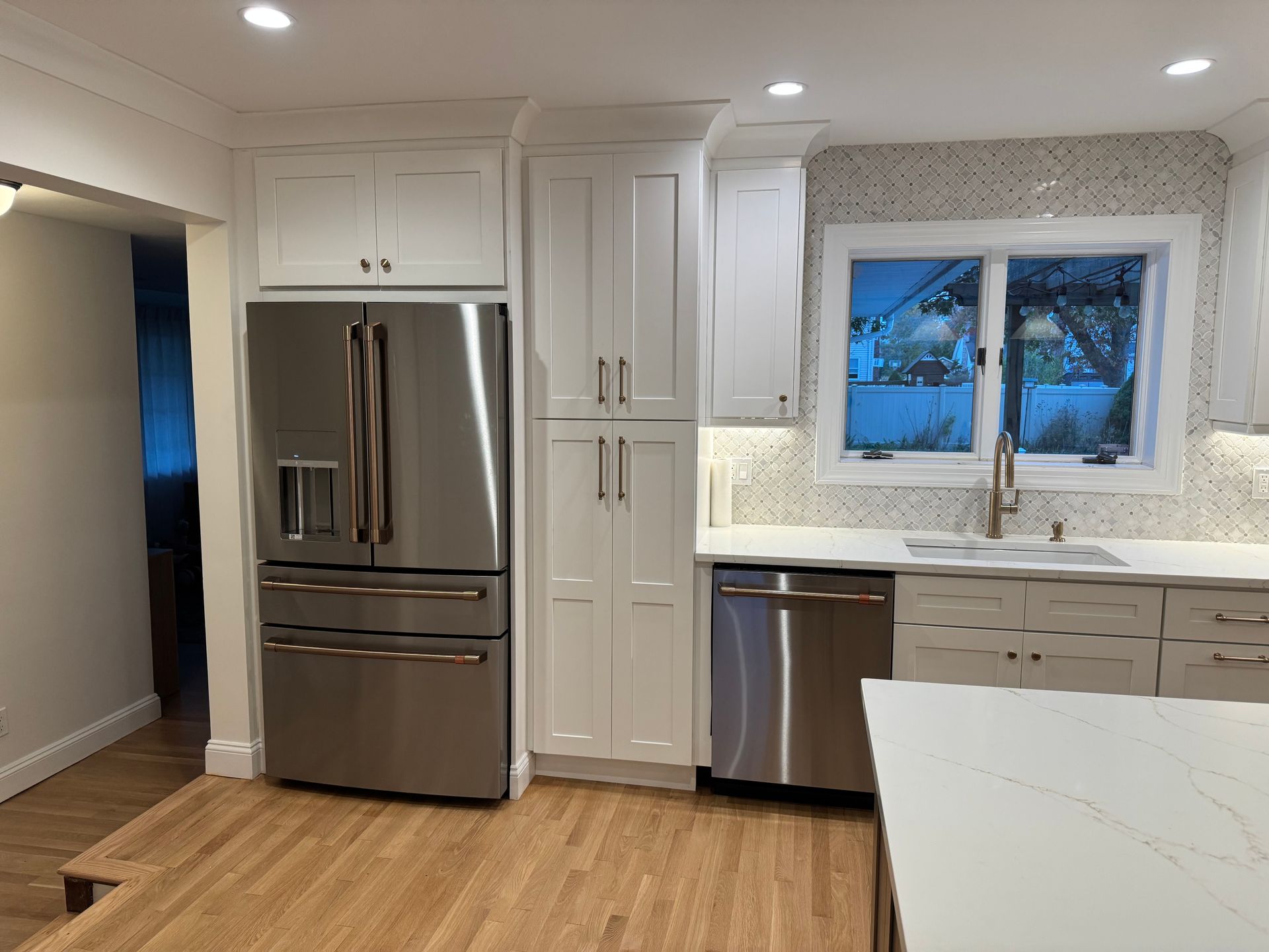 Kitchen with stainless steel appliances, white cabinets, and wooden floor.