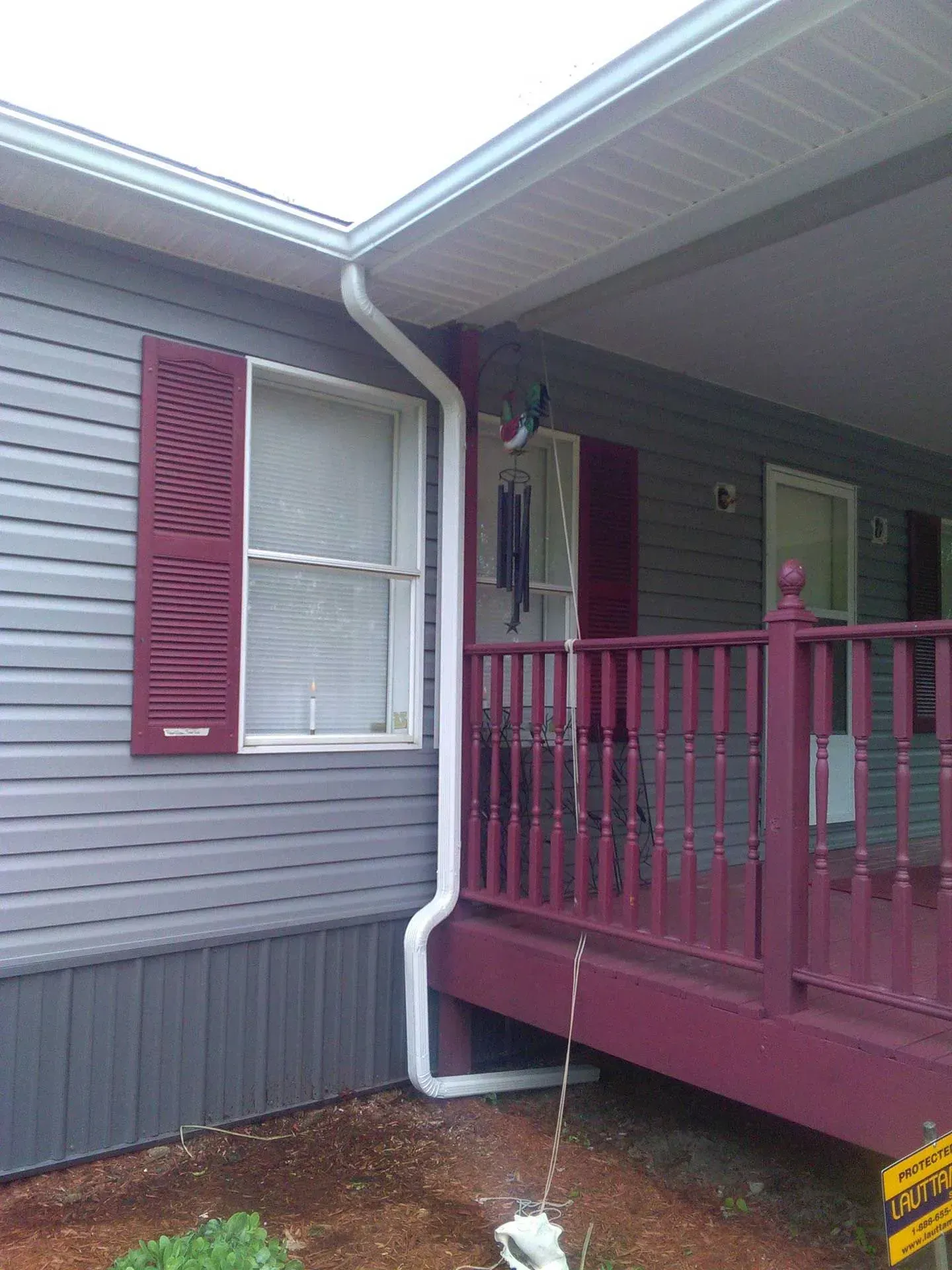 House exterior with gray siding, burgundy trim, and a small burgundy porch with railing and white downspout