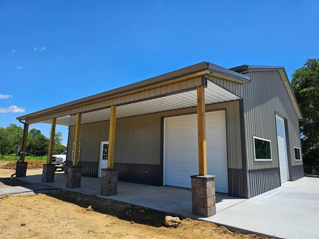Steel-sided building with a porch, concrete pad, and blue sky.