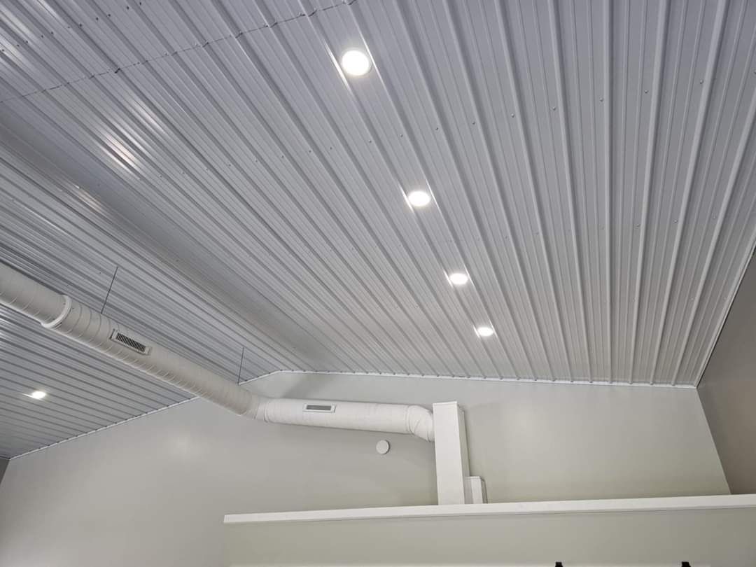 White metal corrugated ceiling with recessed lights and exposed ductwork.