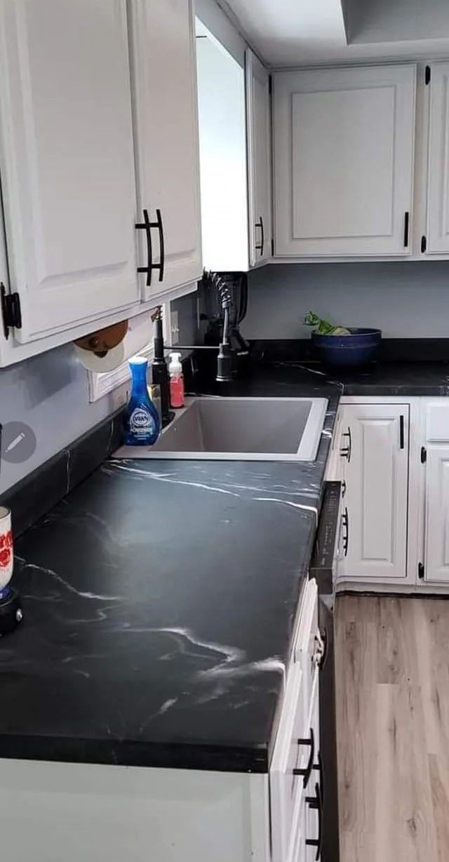 White kitchen cabinets with black countertops, sink, and hardware.