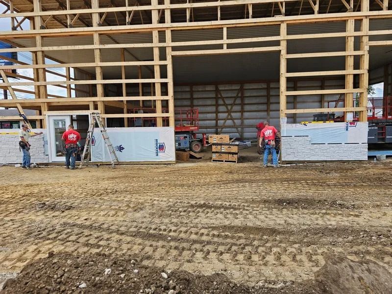 Construction workers installing insulation panels on a wooden framed building, outdoor setting.