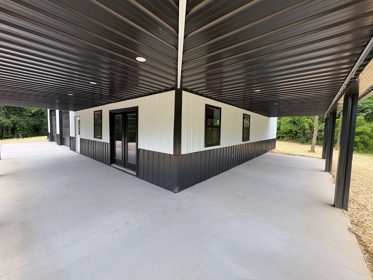 Covered patio with black ceiling and trim, white siding, and concrete floor.