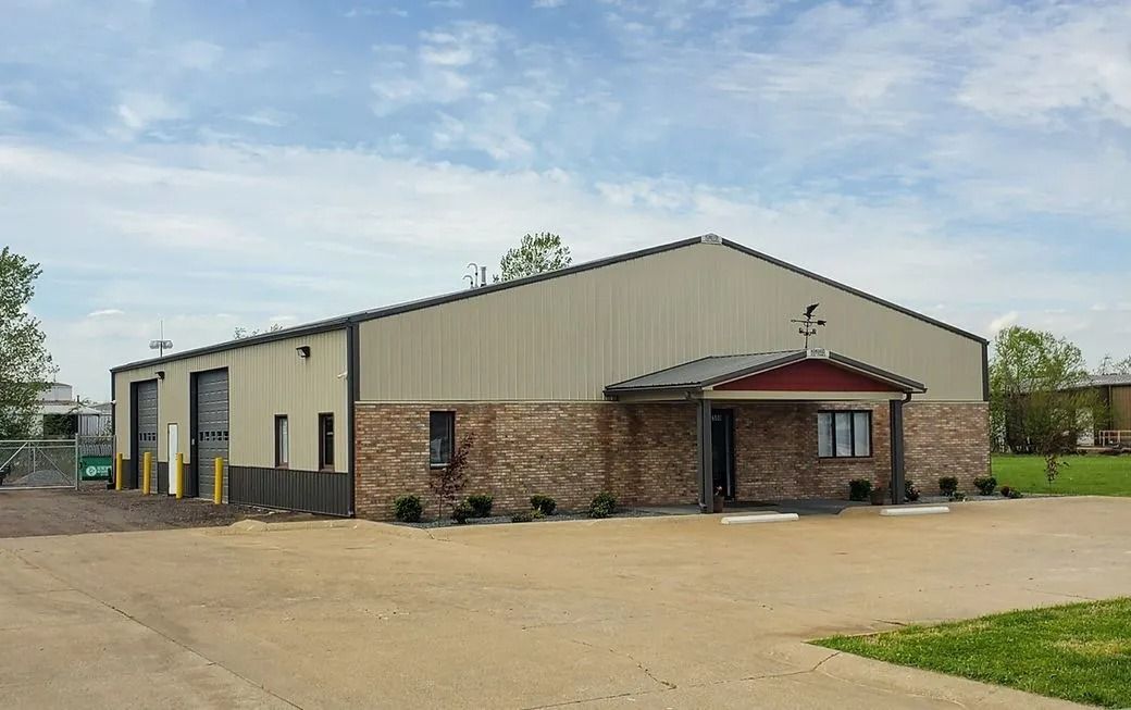 Tan and brown industrial building with a brick facade, under a blue sky.