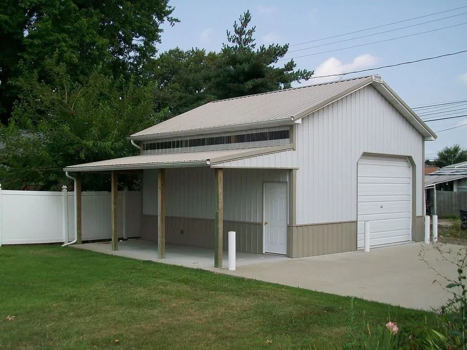 White and tan metal garage with a porch and open garage door on a grassy lawn.