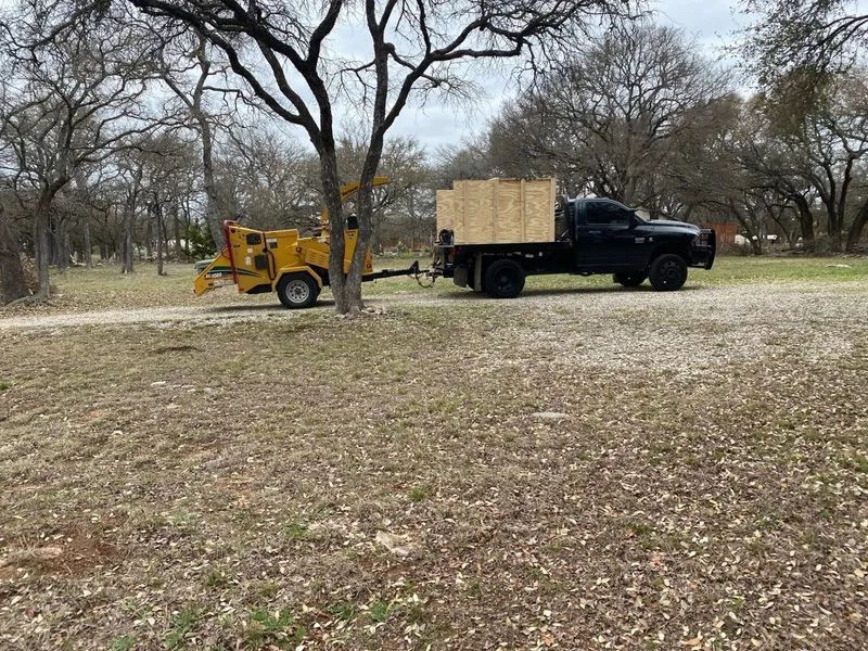 A truck with a tree chipper attached to it is parked in a field.