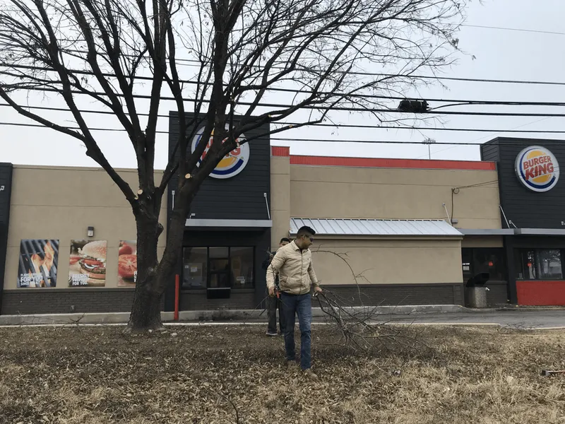 A man is standing in front of a burger king restaurant