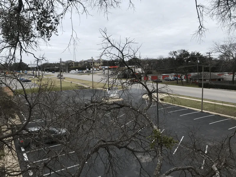 A parking lot with cars parked in it and a tree in the foreground.