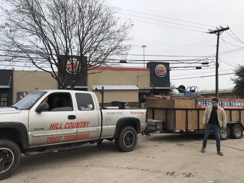 A man is standing next to a hill country truck