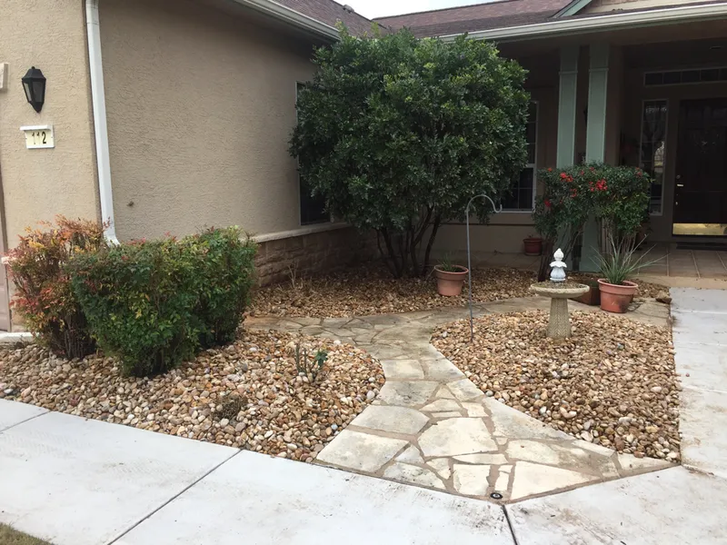 There is a stone walkway leading to the front of the house.