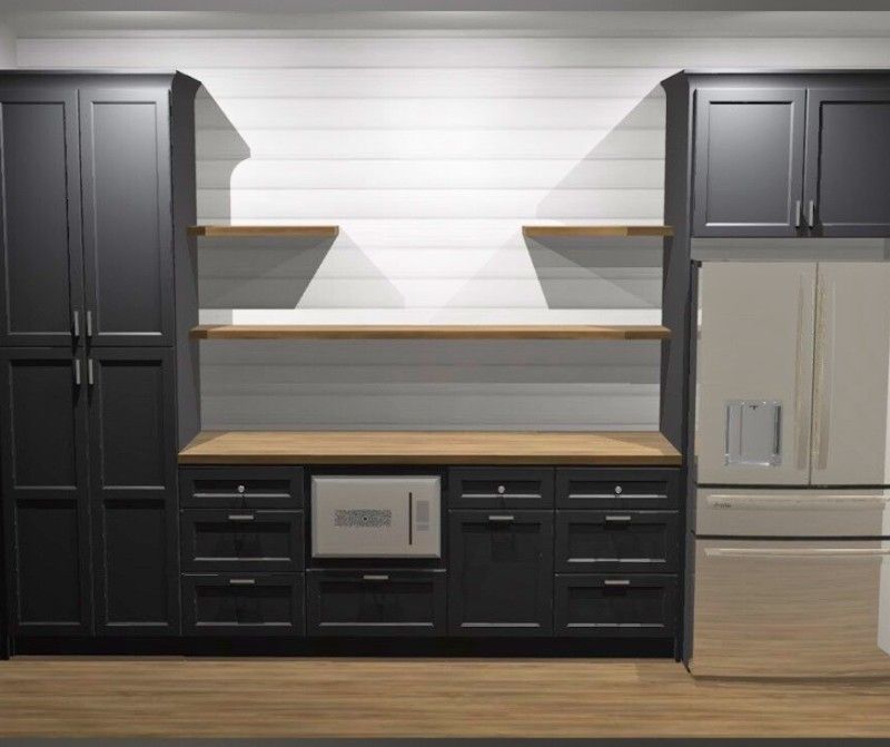 A kitchen with black cabinets , a refrigerator , a microwave and shelves.