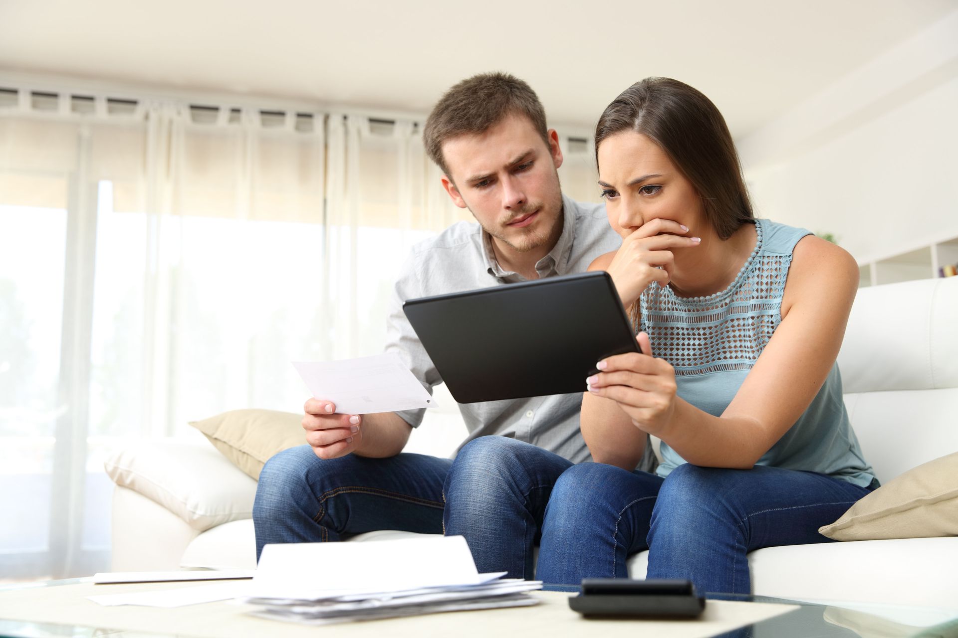 Concerned Iowa couple reviewing a denied workers' compensation claim on a tablet