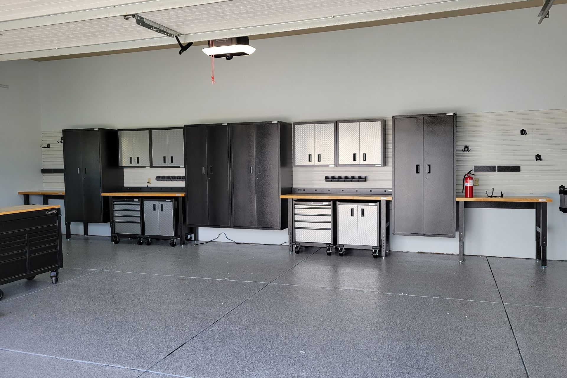 Garage with gray speckled floor, organized storage cabinets, and workbenches.