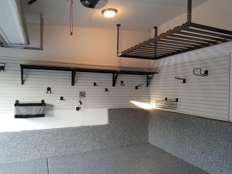 Organized garage with overhead storage, wall shelving, hooks, and a gray floor.
