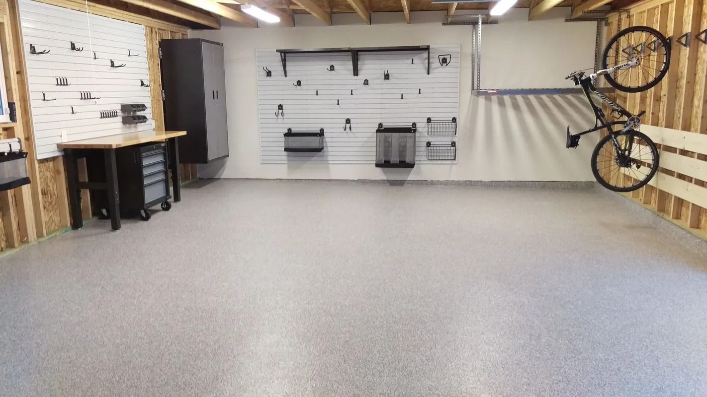 Garage with epoxy floor, tools on pegboards, workbench, and bike on wall.
