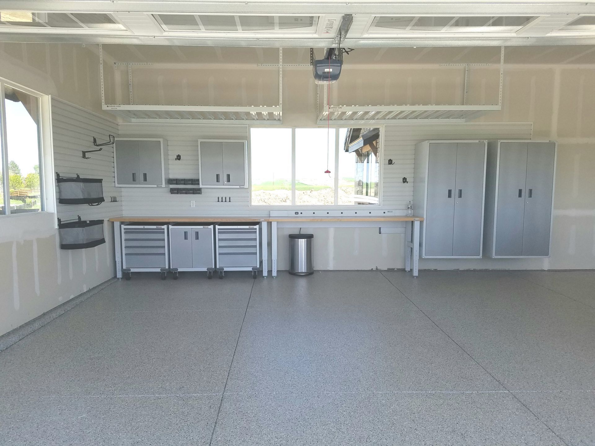 Garage interior with cabinets, workbench, and a speckled gray floor.