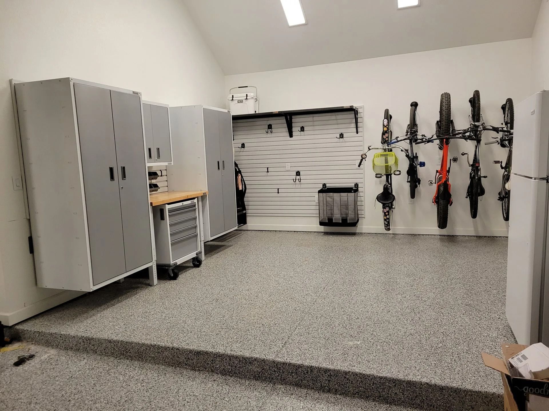 Garage with epoxy floor, storage cabinets, bike racks, and tools.