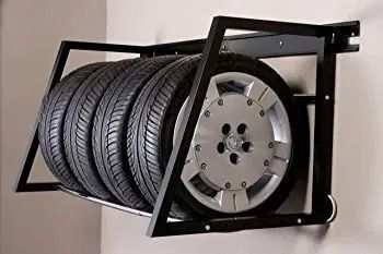 Black metal tire rack mounted on a wall, holding four car tires with silver rims.
